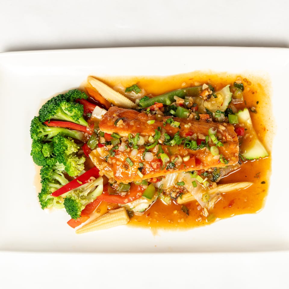 Crispy fish fillets topped with chopped vegetables and scallions, served in a spicy sauce with broccoli, peppers, zucchini, and baby corn.