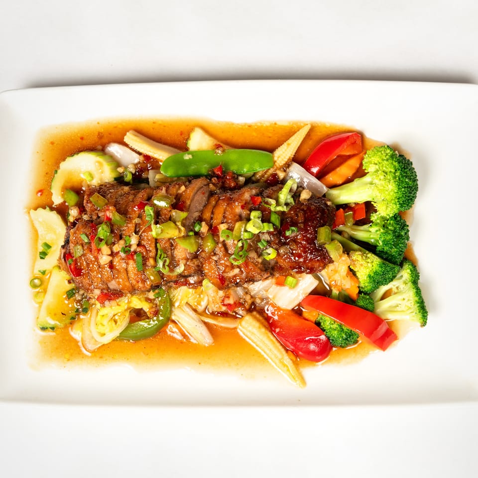 Glazed grilled meat topped with scallions and peppers, served with colorful stir-fried vegetables in savory sauce.